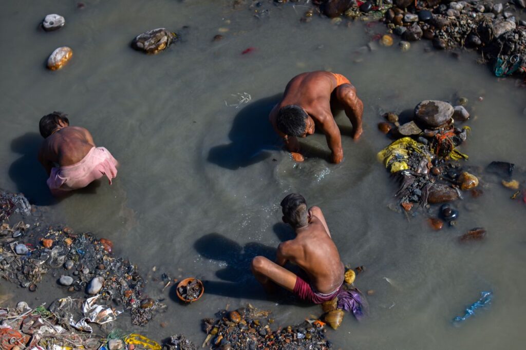 Three men working in a river in Haridwar, India, gathering stones. Aerial view.